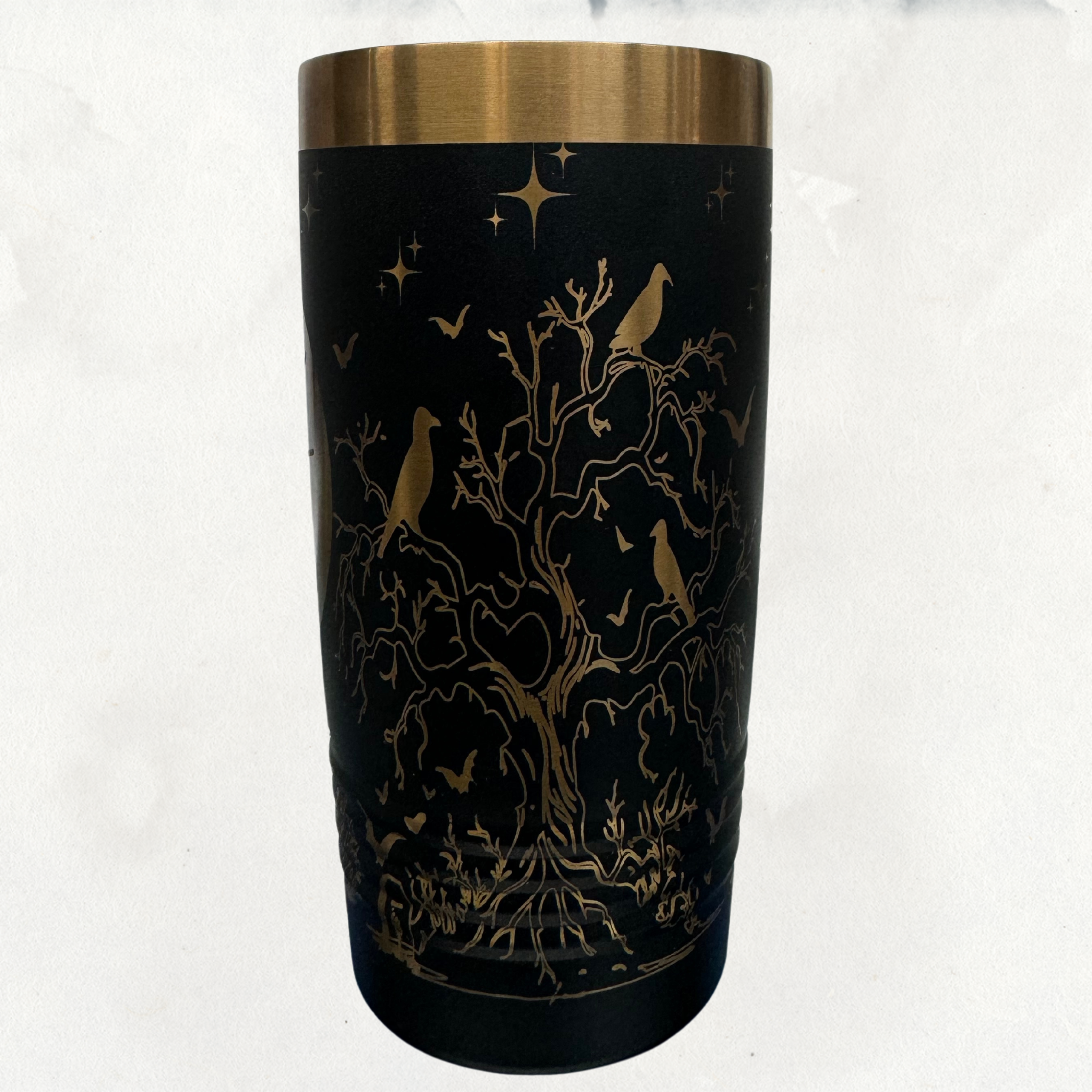 Black 20 oz laser-etched tumbler with gold accents, featuring a detailed spooky tree design with ravens, bats, and stars, ideal for Halloween-themed or gothic-style drinkware.