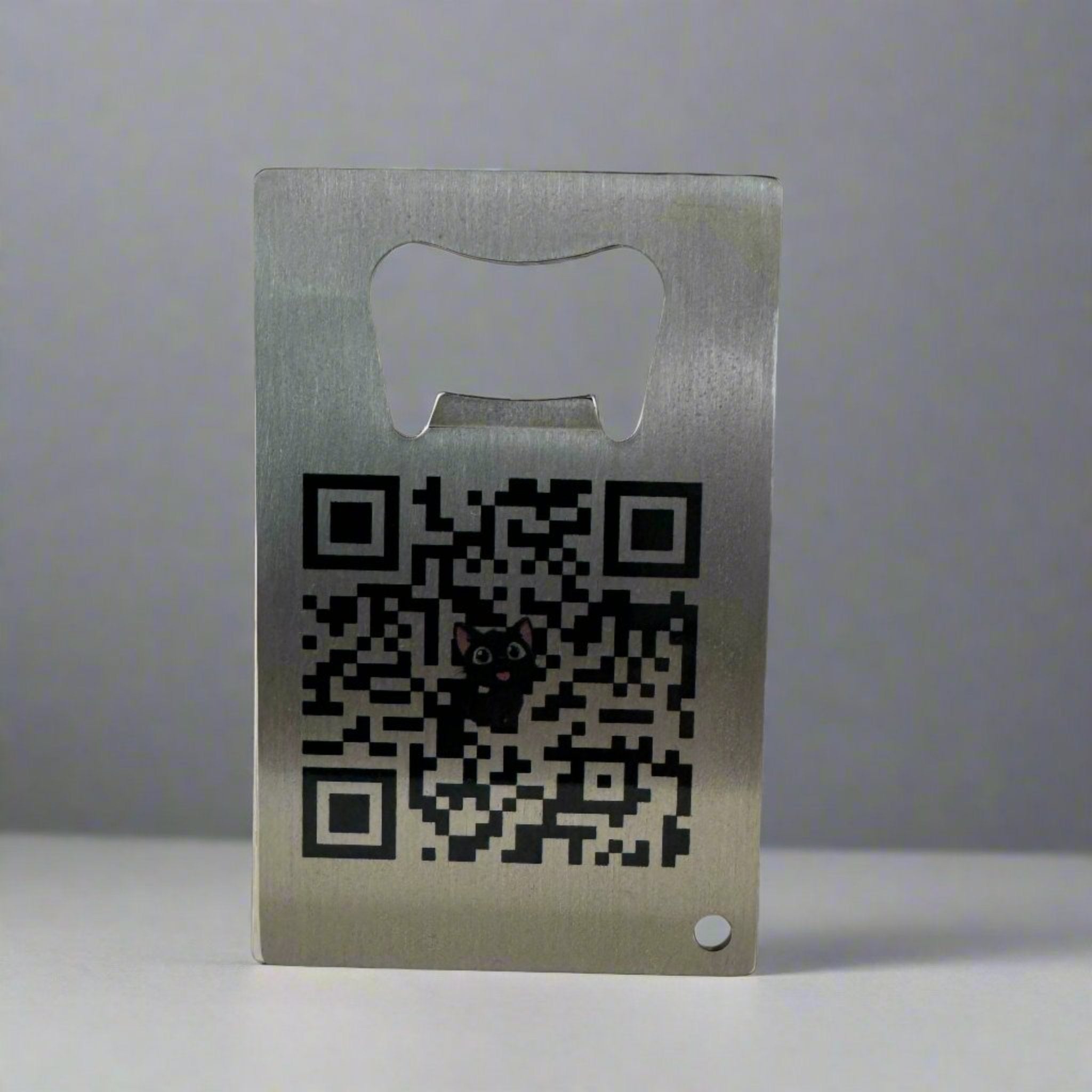 Metal custom bottle opener business card featuring a prominent QR code with a small cartoon cat in the center, designed for digital connectivity and tech branding.