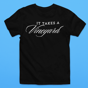 A black t-shirt with the phrase "It Takes a Vineyard" Short Sleeve T-Shirt printed on the front in white. The word "Vineyard" is styled in an elegant, cursive font. Perfect for those who celebrate motherhood and enjoy wine, this shirt offers both comfort and style against a solid light blue backdrop.