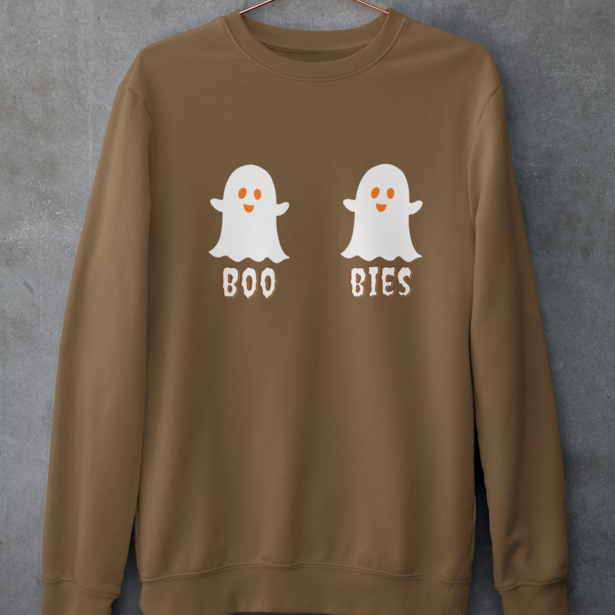 Brown cozy Halloween sweatshirt featuring two cute ghost illustrations with the playful text "BOO BIES," hanging against a gray background, perfect for festive casual wear.