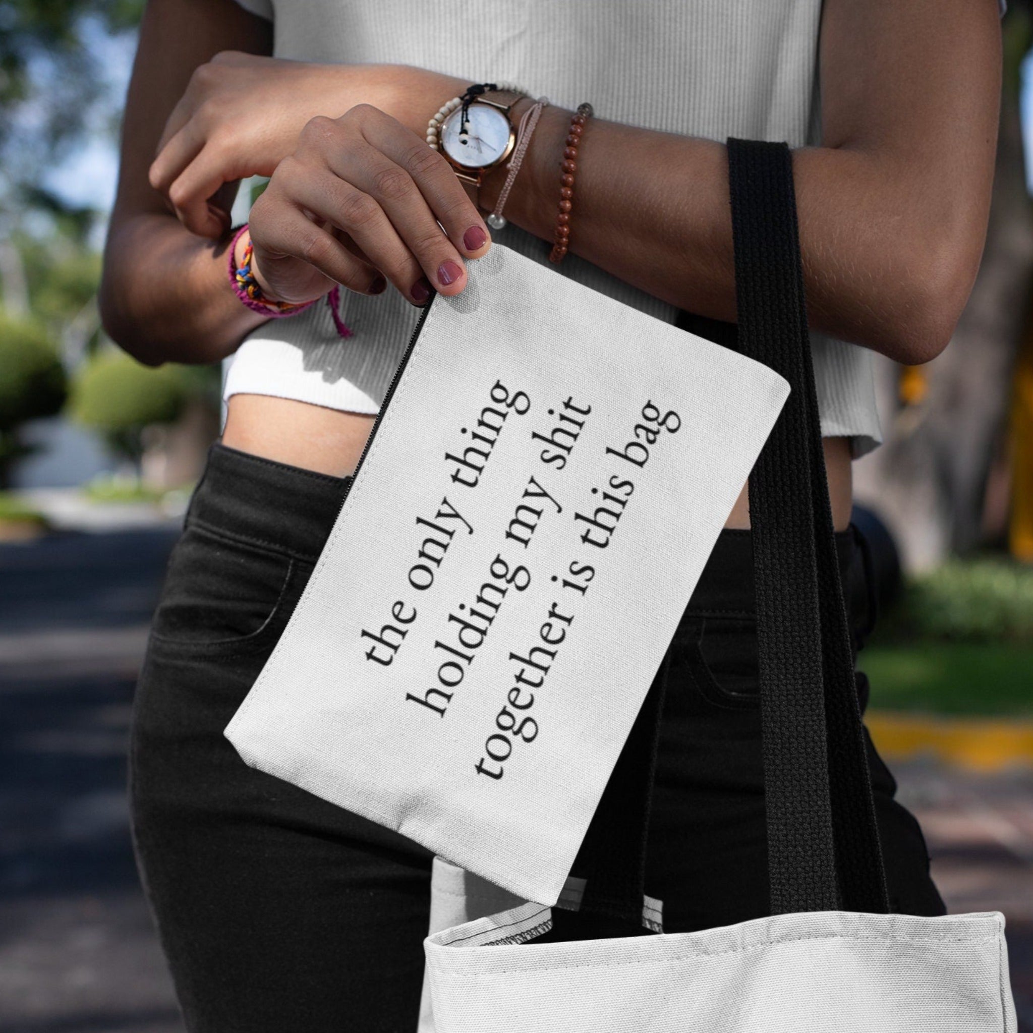 A woman carrying a custom makeup bag with the phrase 'The Only Thing Holding My Shit Together Is This Bag,' making it a funny and practical gift for women. Perfect for those looking for unique and humorous cosmetic bags.