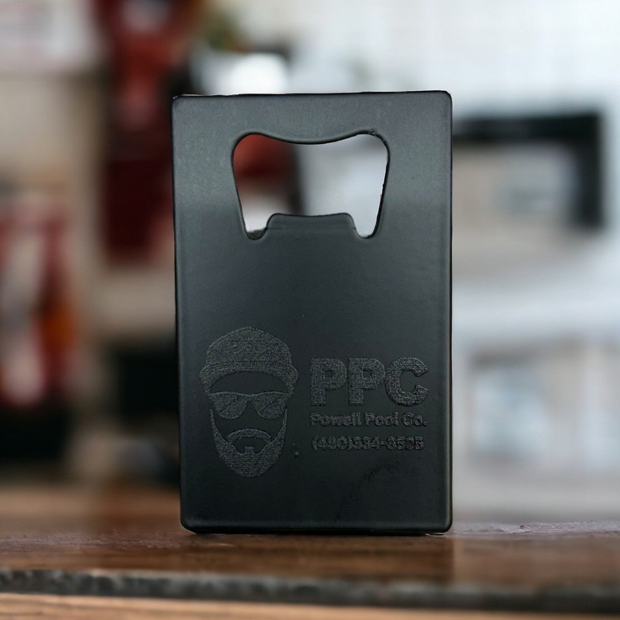 Black custom bottle opener business card with "PPC Powell Pool Co." logo, featuring a bearded man in sunglasses and hat, designed for pool service branding and marketing purposes.